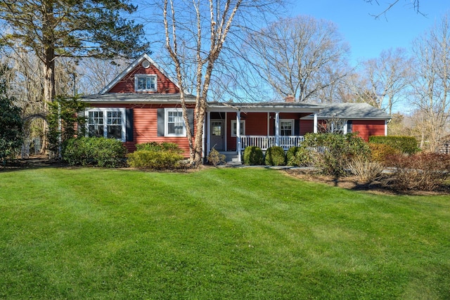 view of front facade with covered porch, a chimney, and a front yard