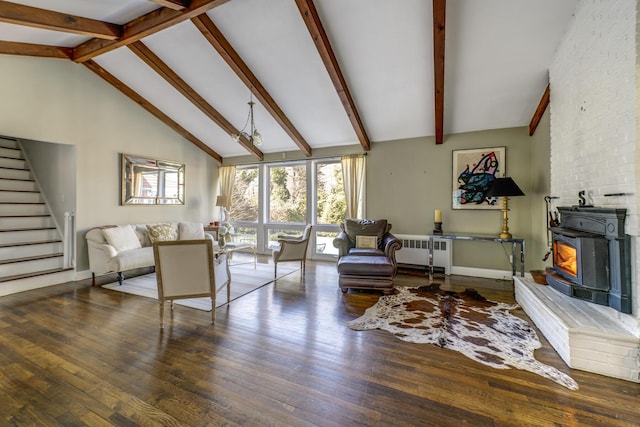 living area featuring stairway, beam ceiling, hardwood / wood-style floors, radiator heating unit, and a wood stove