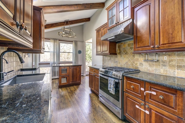 kitchen featuring dark wood finished floors, a sink, stainless steel gas range, dark stone counters, and under cabinet range hood