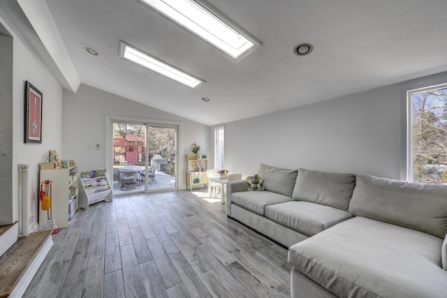 living room featuring vaulted ceiling with skylight and wood finished floors