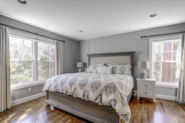 bedroom with multiple windows, baseboards, and wood finished floors