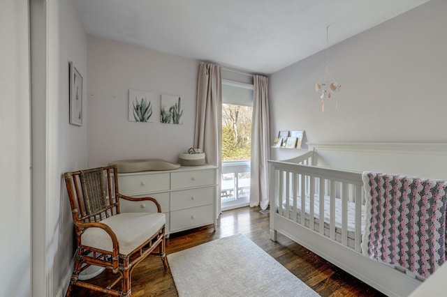 bedroom featuring a crib and dark wood-style flooring