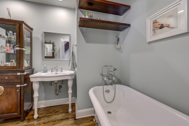 full bathroom with baseboards, a freestanding bath, and wood finished floors