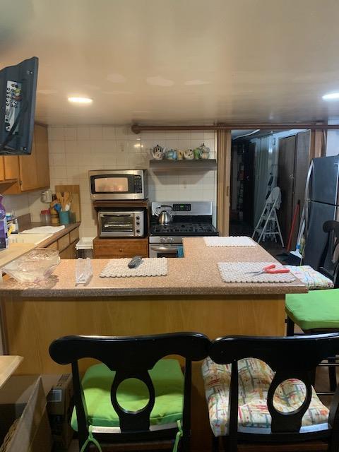 kitchen with a toaster, a breakfast bar area, stainless steel appliances, tasteful backsplash, and a peninsula