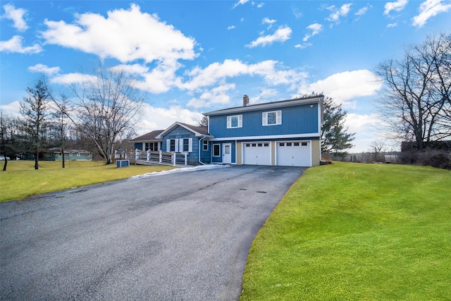 view of front of home featuring a front yard, an attached garage, a chimney, and aphalt driveway