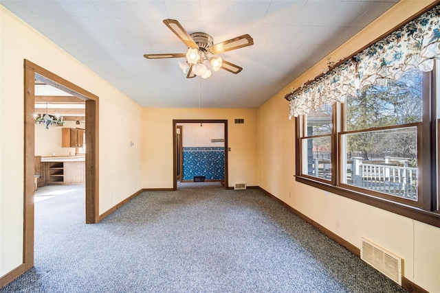 unfurnished room with visible vents, carpet floors, baseboards, and a ceiling fan