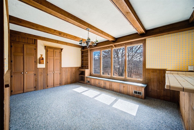 unfurnished sunroom featuring beam ceiling and a chandelier