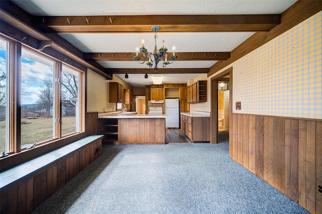 kitchen featuring a wainscoted wall, beamed ceiling, freestanding refrigerator, brown cabinetry, and a chandelier