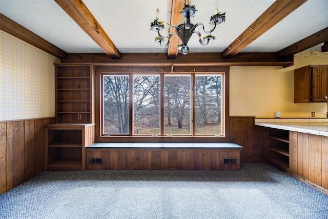 unfurnished dining area featuring wallpapered walls, carpet flooring, visible vents, and a wainscoted wall