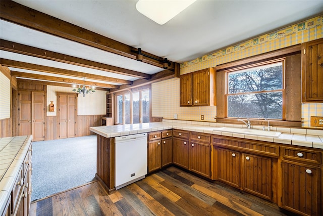 kitchen featuring beam ceiling, a peninsula, white dishwasher, a sink, and tile counters