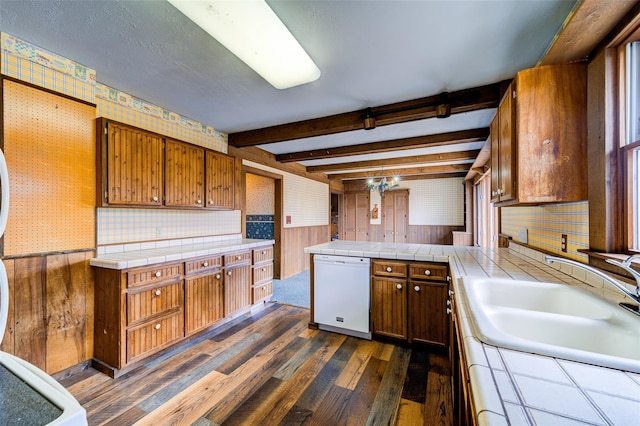 kitchen with beamed ceiling, dishwasher, wallpapered walls, and a sink