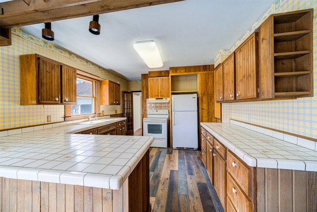 kitchen with open shelves, white appliances, tile counters, and a sink