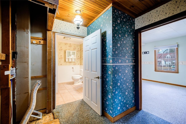 hallway with carpet floors, wood ceiling, wainscoting, and wallpapered walls