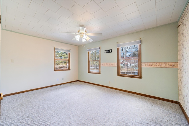 carpeted empty room with baseboards, a healthy amount of sunlight, wallpapered walls, and ceiling fan