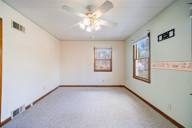 carpeted spare room featuring visible vents, ceiling fan, and ornamental molding