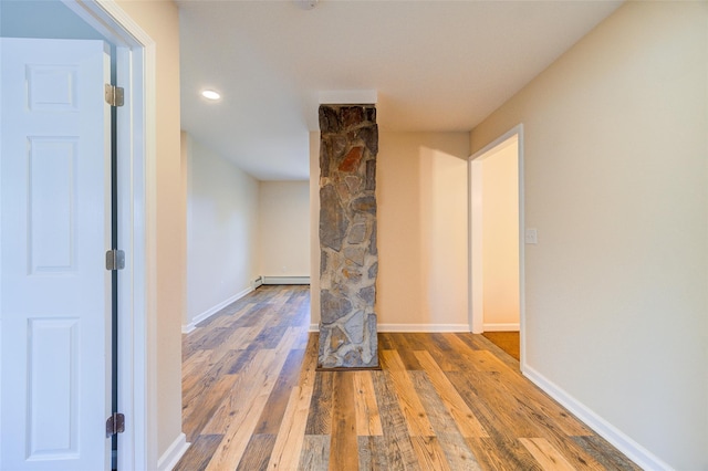 interior space with a baseboard radiator, baseboards, and hardwood / wood-style floors