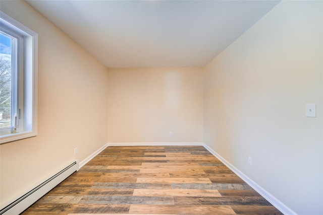 unfurnished room featuring baseboard heating, baseboards, and wood finished floors