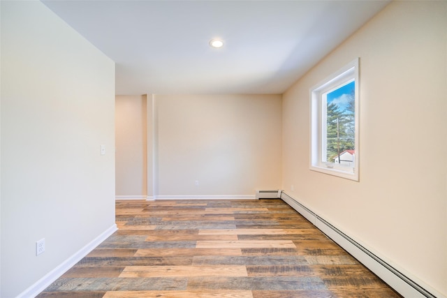 unfurnished room with baseboards, baseboard heating, and wood finished floors