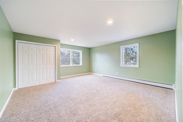 unfurnished bedroom with baseboards, a baseboard heating unit, carpet floors, and a closet