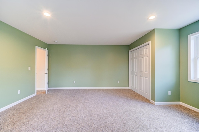 unfurnished bedroom with recessed lighting, light colored carpet, baseboards, and a closet