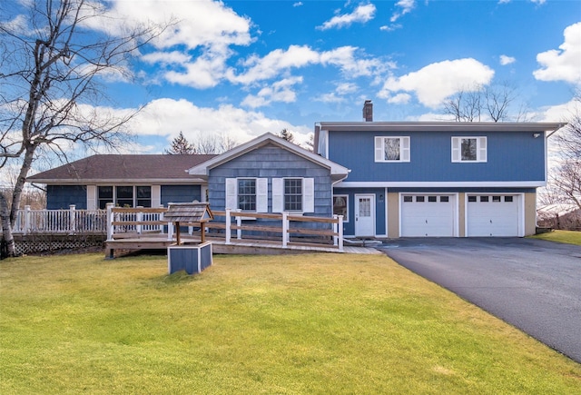 view of front of property with a front lawn, a wooden deck, a chimney, a garage, and driveway