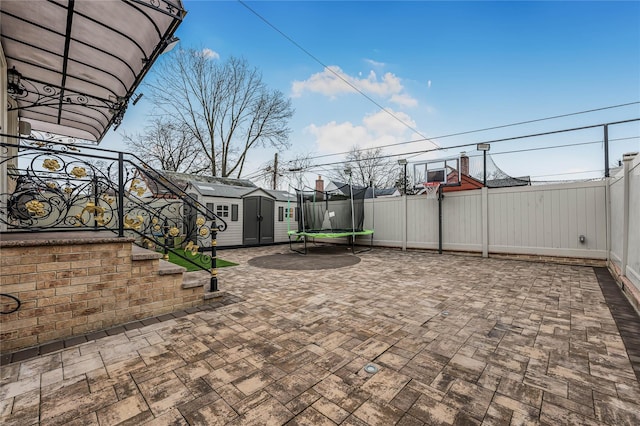 view of patio with a trampoline, an outdoor structure, a storage shed, and fence