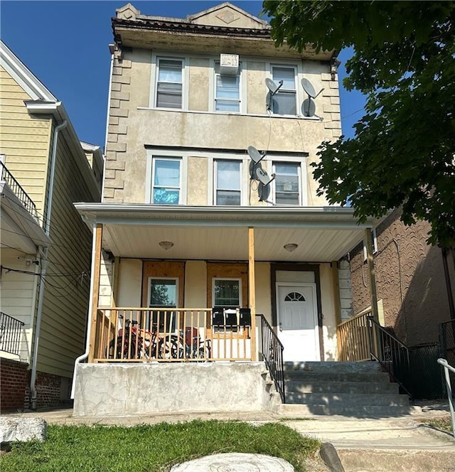 american foursquare style home with covered porch and stucco siding