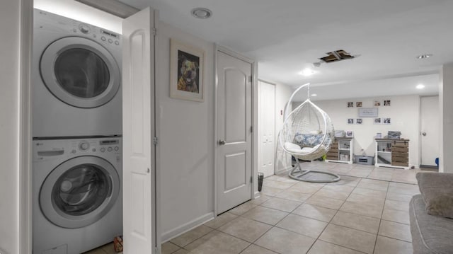 laundry area with stacked washing maching and dryer, light tile patterned floors, and laundry area