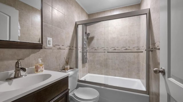 full bathroom with tasteful backsplash, toilet, shower / bath combination with glass door, vanity, and tile walls