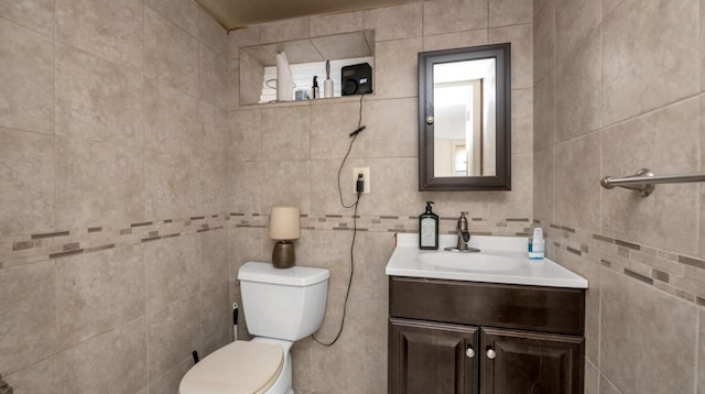 bathroom with vanity, toilet, and tile walls