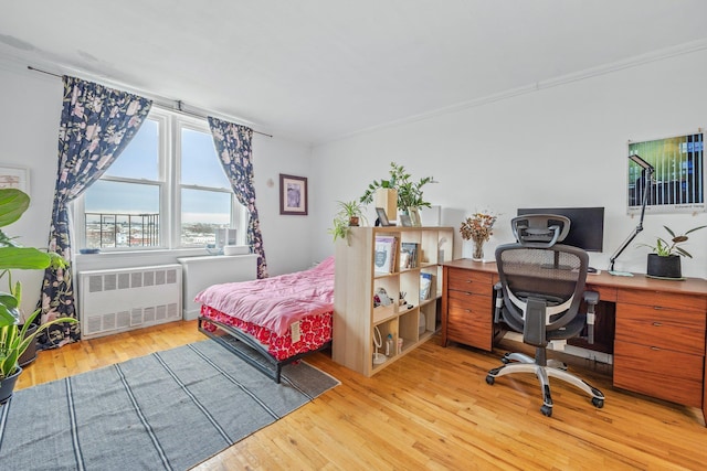 bedroom featuring light wood-type flooring, crown molding, and radiator heating unit