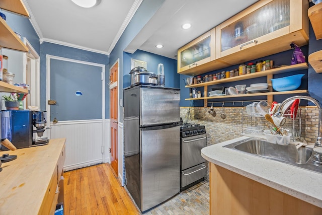 kitchen featuring open shelves, gas range oven, ornamental molding, freestanding refrigerator, and wainscoting