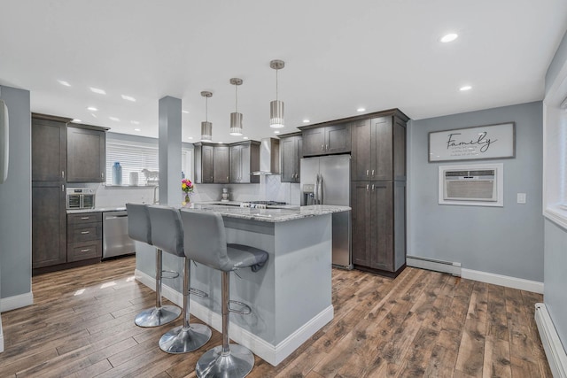 kitchen featuring appliances with stainless steel finishes, baseboard heating, a wall mounted air conditioner, and wall chimney exhaust hood