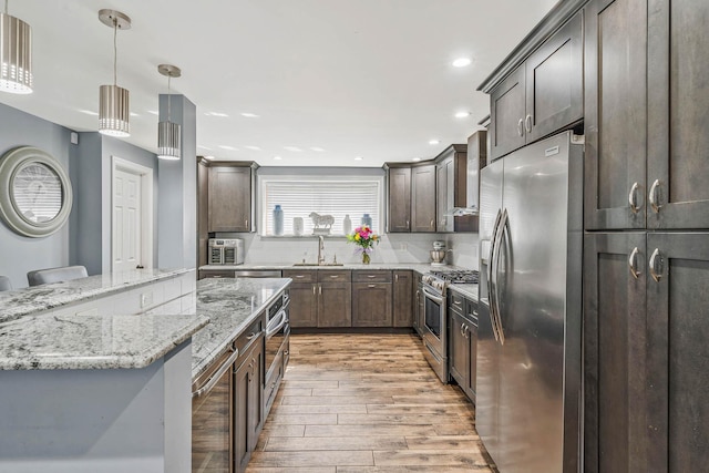 kitchen with tasteful backsplash, beverage cooler, light wood-style flooring, appliances with stainless steel finishes, and light stone countertops