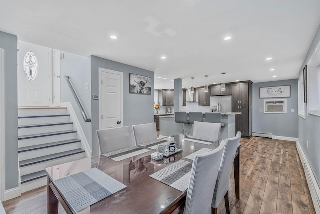 dining room with a wall unit AC, a baseboard radiator, wood finished floors, and recessed lighting