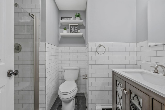 full bath with a wainscoted wall, tile walls, toilet, a tile shower, and vanity