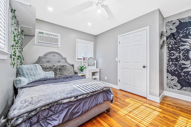 bedroom featuring recessed lighting, a wall mounted AC, light wood-style floors, ceiling fan, and baseboards