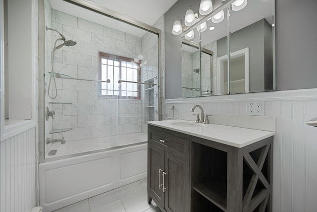 full bath with tile patterned floors, vanity, combined bath / shower with glass door, and wainscoting