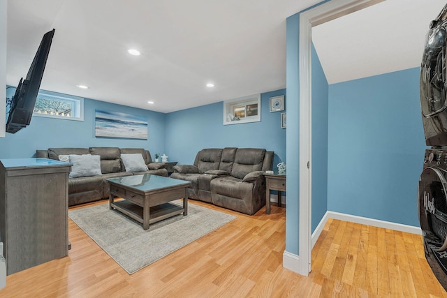 living area featuring light wood-type flooring, stacked washer and clothes dryer, baseboards, and recessed lighting