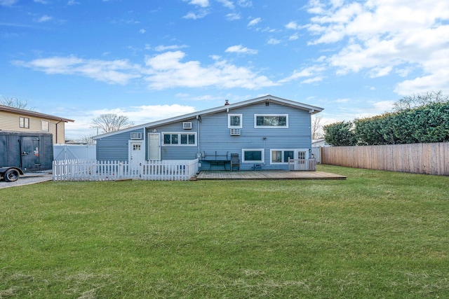 rear view of property with a deck, a yard, and fence