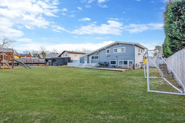 back of house featuring a fenced backyard, a lawn, a deck, and a playground