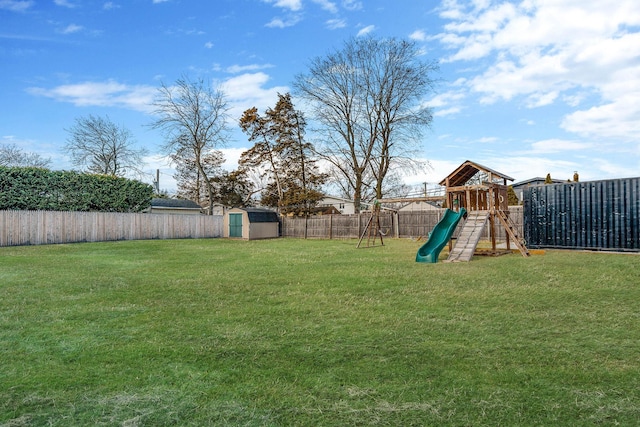 view of yard featuring a playground, a shed, an outdoor structure, and a fenced backyard