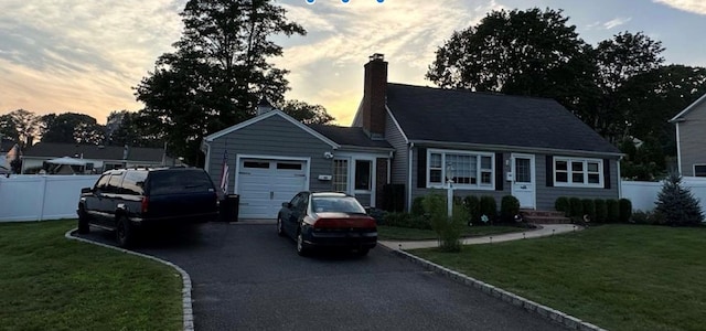 view of front of property featuring driveway, an attached garage, fence, and a front yard