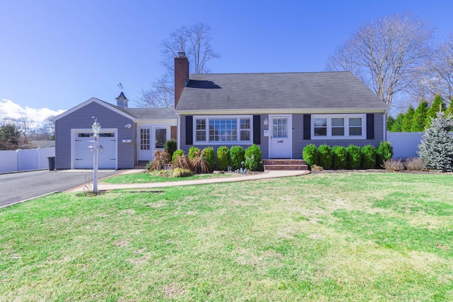 view of front of house with an attached garage, fence, driveway, a front lawn, and a chimney