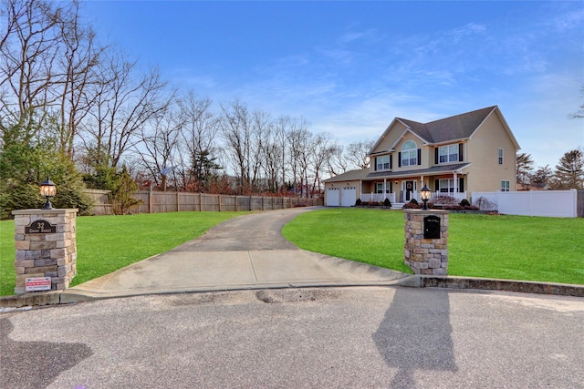 view of front of house with aphalt driveway, covered porch, fence, and a front lawn