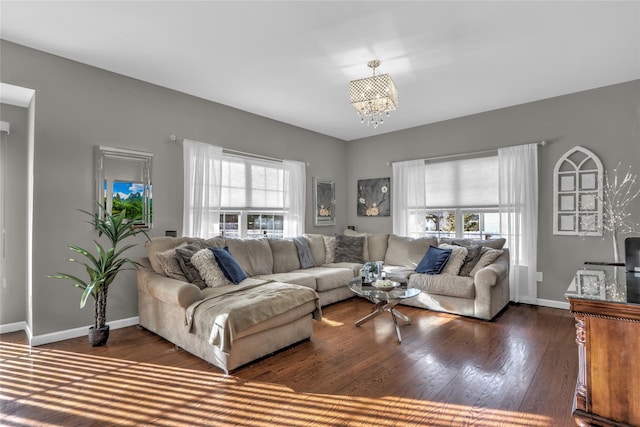 living room with dark wood-style floors, a notable chandelier, a wealth of natural light, and baseboards