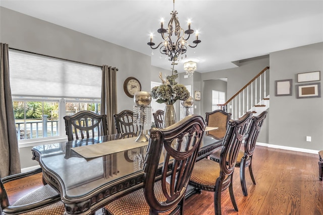 dining space featuring a chandelier, baseboards, and wood finished floors