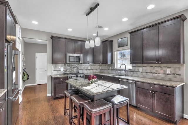 kitchen with dark brown cabinetry, visible vents, dark wood finished floors, stainless steel appliances, and a sink