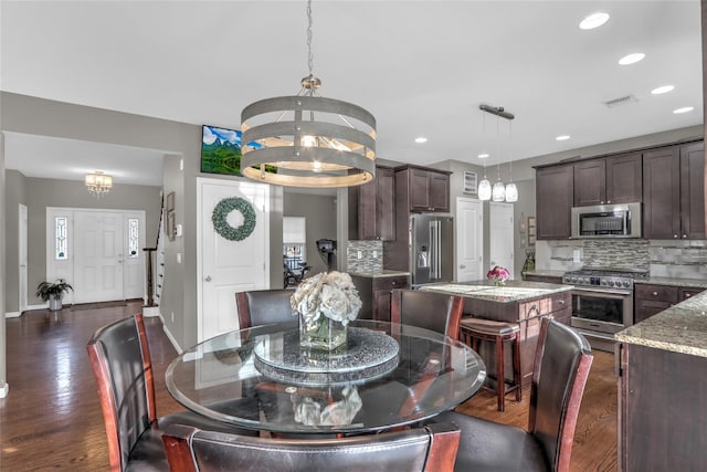 dining space featuring a chandelier, visible vents, baseboards, and dark wood-style floors