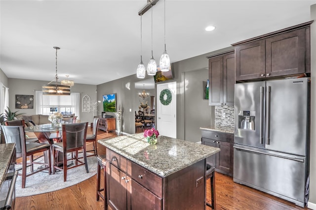 kitchen with a kitchen bar, high quality fridge, a kitchen island, and wood finished floors